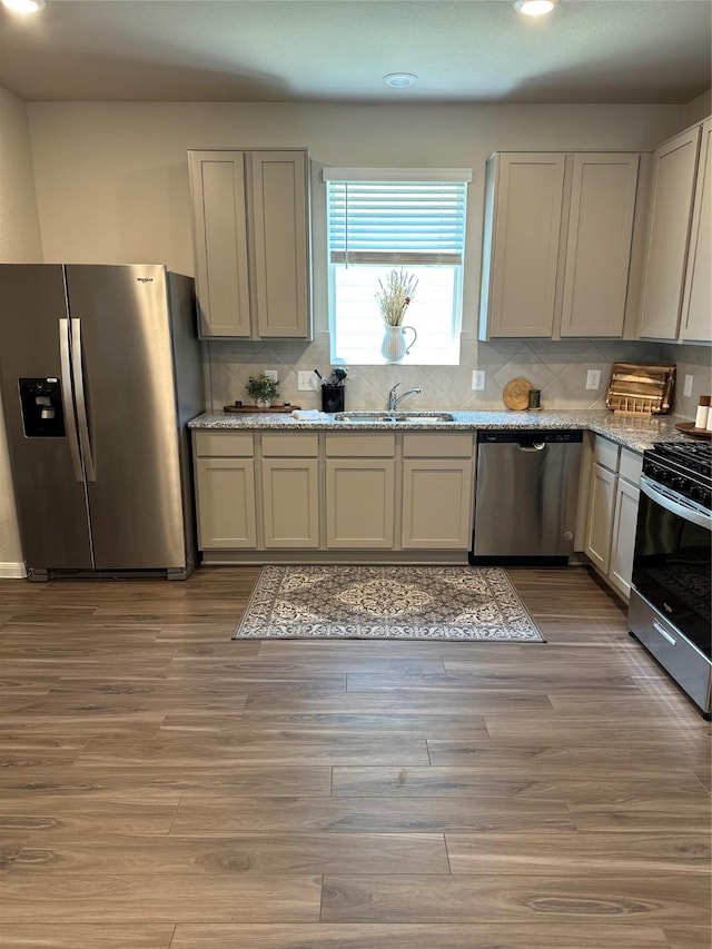 13556 Bowfin Dr, Conroe, TX 77384 - kitchen featuring stainless steel appliances, recessed lighting, a sink, backsplash, and light stone countertops