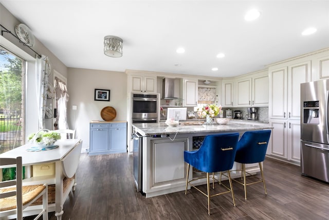 8219 Magnolia Glen Dr, Humble, TX 77346 - kitchen with appliances with stainless steel finishes, wall chimney range hood, light stone counters, a center island, and dark wood finished floors