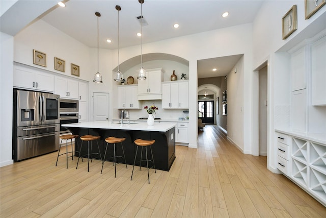 23619 Bottlebrush Terrace Trl, Katy, TX 77493 - kitchen with stainless steel appliances, a sink, a kitchen bar, light countertops, and light wood-type flooring