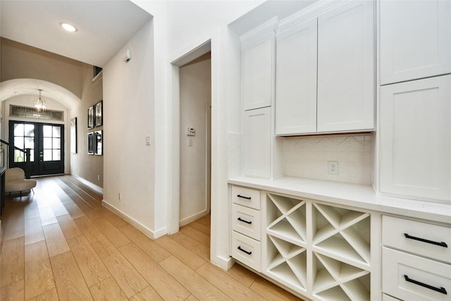 23619 Bottlebrush Terrace Trl, Katy, TX 77493 - bar area featuring arched walkways, light wood-style floors, baseboards, tasteful backsplash, and french doors