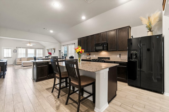 15111 Raffia Leaves Way, Houston, TX 77090 - kitchen with black appliances, lofted ceiling, a kitchen island, open floor plan, and light wood-type flooring