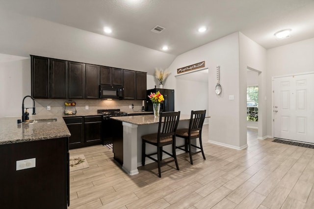 15111 Raffia Leaves Way, Houston, TX 77090 - kitchen with black appliances, a sink, a kitchen breakfast bar, tasteful backsplash, and light stone countertops