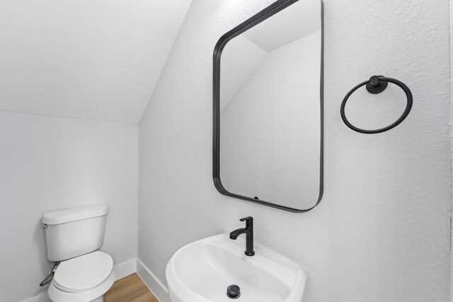 6631 Foster St, Houston, TX 77021 - half bathroom featuring lofted ceiling, toilet, wood finished floors, a sink, and baseboards