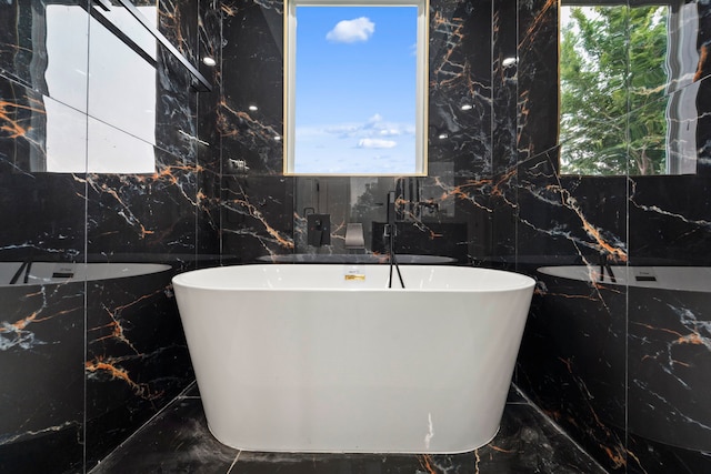 6631 Foster St, Houston, TX 77021 - bathroom with marble tiled floors, a freestanding bath, tile walls, and a sink