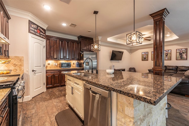 2323 Foley Rd, Crosby, TX 77532 - kitchen featuring appliances with stainless steel finishes, ornate columns, a kitchen island with sink, ornamental molding, and tasteful backsplash