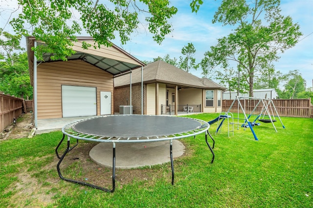 2323 Foley Rd, Crosby, TX 77532 - rear view of property with a trampoline, a playground, a fenced backyard, and a detached garage
