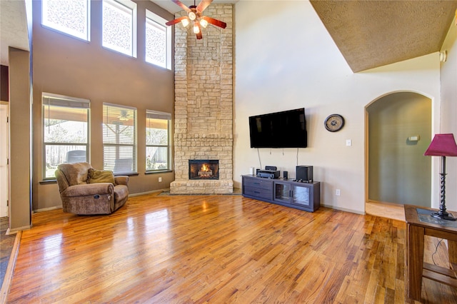 19902 Dayton Ridge Ln, Cypress, TX 77433 - living area featuring a towering ceiling, arched walkways, wood finished floors, a ceiling fan, and a fireplace