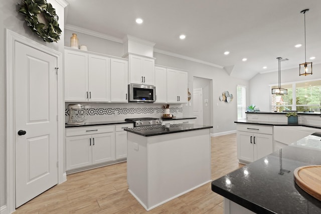 1603 Country Club Dr, Crosby, TX 77532 - kitchen featuring stainless steel microwave, backsplash, a center island, ornamental molding, and white cabinets