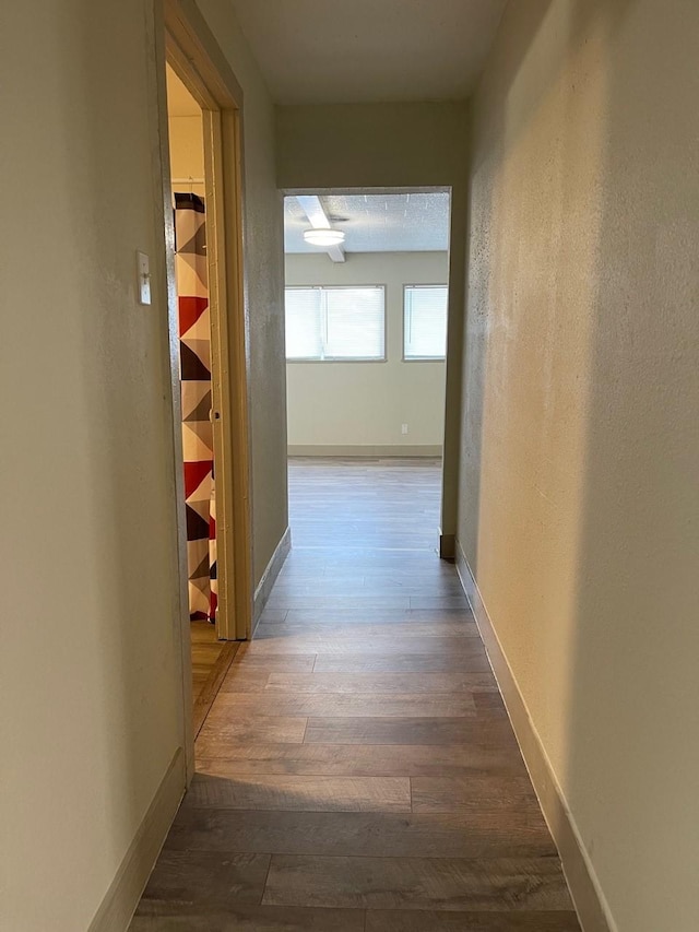 1602 W Blum St, Alvin, TX 77511 - hallway with dark wood-style flooring, baseboards, and a textured wall