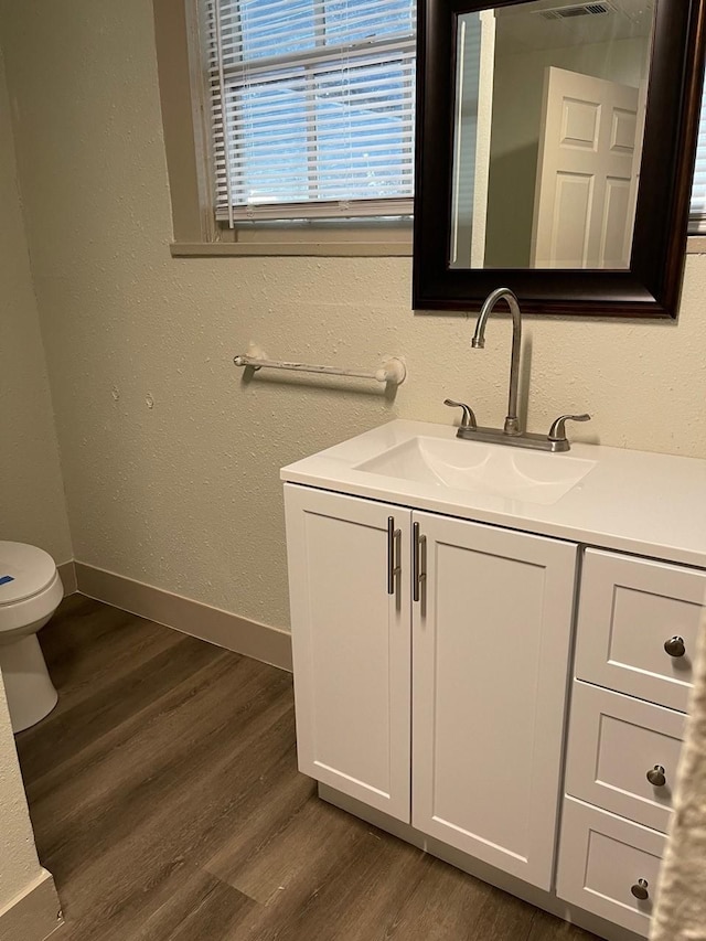 1602 W Blum St, Alvin, TX 77511 - bathroom featuring toilet, wood finished floors, vanity, a textured wall, and baseboards