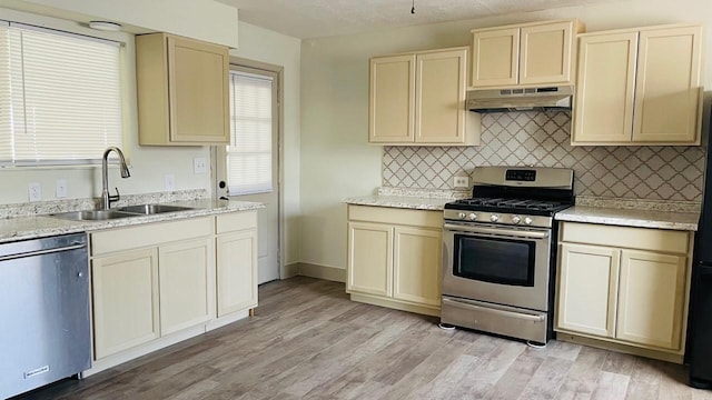 1602 W Blum St, Alvin, TX 77511 - kitchen featuring appliances with stainless steel finishes, under cabinet range hood, a sink, cream cabinetry, and decorative backsplash