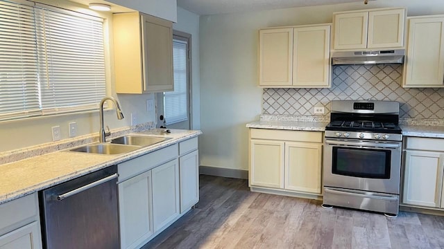 1602 W Blum St, Alvin, TX 77511 - kitchen featuring under cabinet range hood, stainless steel appliances, a sink, and decorative backsplash