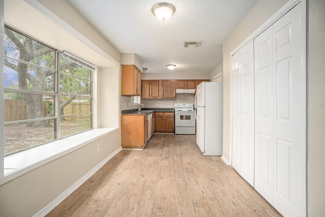 4875 Beechaven St, Houston, TX 77053 - kitchen featuring white appliances, light wood-style flooring, a sink, brown cabinetry, and a textured ceiling