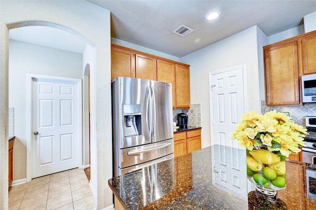 5838 Deleon Trail Dr, Spring, TX 77379 - kitchen featuring stainless steel refrigerator with ice dispenser, arched walkways, decorative backsplash, white microwave, and recessed lighting