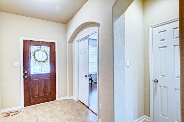 5838 Deleon Trail Dr, Spring, TX 77379 - foyer entrance featuring arched walkways, light tile patterned floors, baseboards, and a textured wall