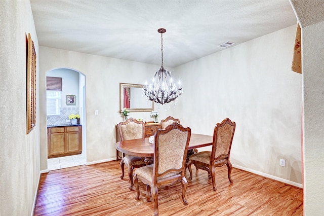 5838 Deleon Trail Dr, Spring, TX 77379 - dining space featuring arched walkways, light wood finished floors, and a chandelier
