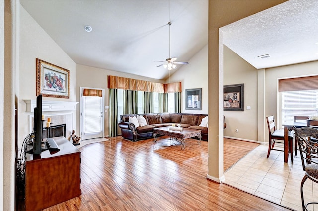 5838 Deleon Trail Dr, Spring, TX 77379 - living area featuring lofted ceiling, a ceiling fan, light wood finished floors, a fireplace, and baseboards