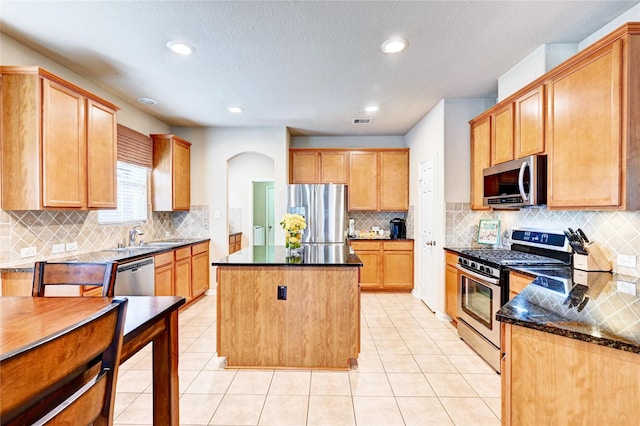 5838 Deleon Trail Dr, Spring, TX 77379 - kitchen with appliances with stainless steel finishes, backsplash, a kitchen island, a sink, and dark stone counters