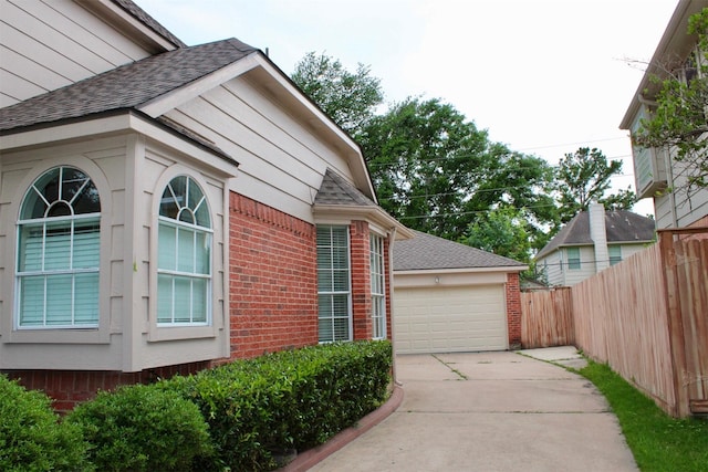 9619 Therrell Dr, Houston, TX 77064 - view of side of home featuring brick siding, concrete driveway, a garage, and a shingled roof