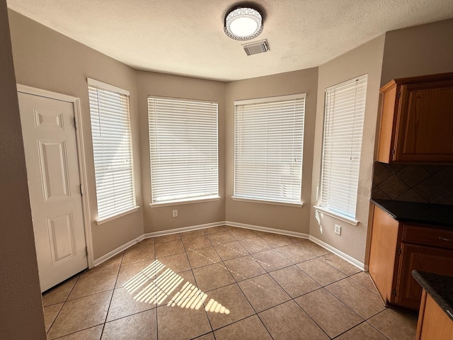 9619 Therrell Dr, Houston, TX 77064 - unfurnished dining area featuring light tile patterned floors, baseboards, and a textured ceiling