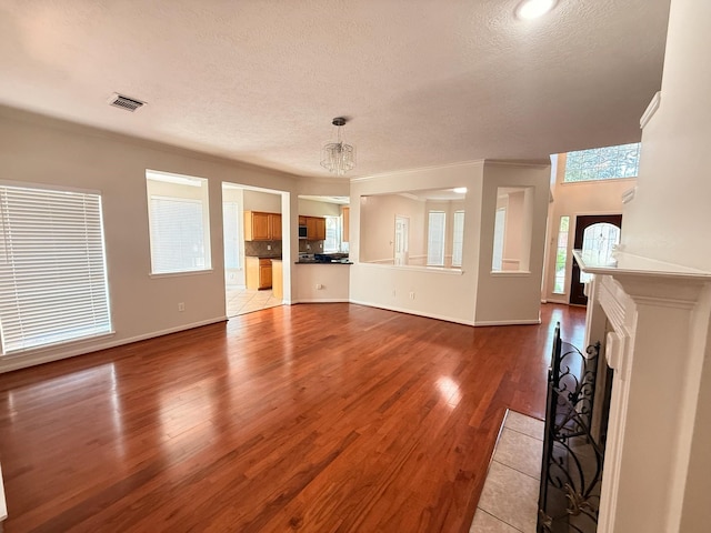 9619 Therrell Dr, Houston, TX 77064 - unfurnished living room featuring a textured ceiling, wood finished floors, a chandelier, baseboards, and a fireplace