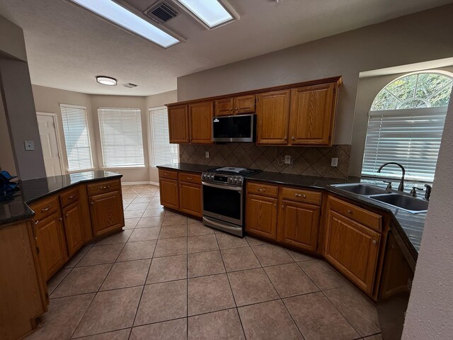 9619 Therrell Dr, Houston, TX 77064 - kitchen with stainless steel appliances, a sink, tasteful backsplash, dark countertops, and light tile patterned flooring