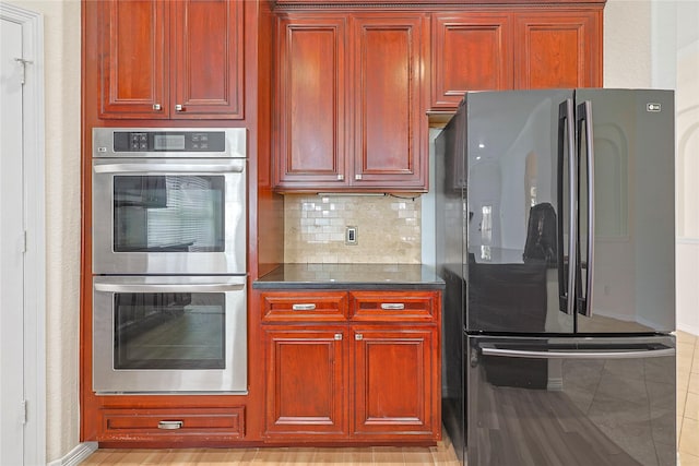 4907 Sundance Hollow Ln, Katy, TX 77494 - kitchen featuring freestanding refrigerator, double oven, reddish brown cabinets, and dark countertops