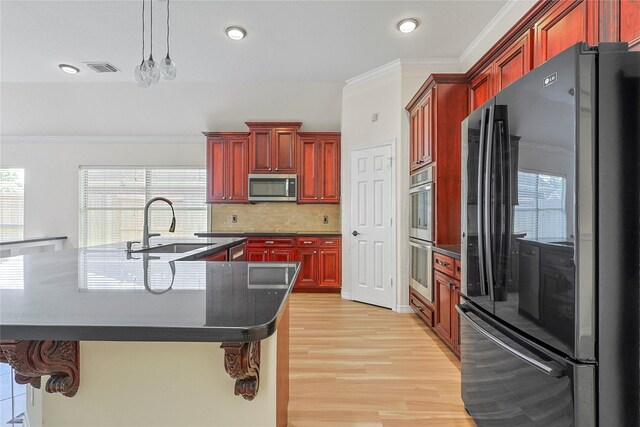 4907 Sundance Hollow Ln, Katy, TX 77494 - kitchen with appliances with stainless steel finishes, dark brown cabinets, dark countertops, light wood finished floors, and healthy amount of natural light