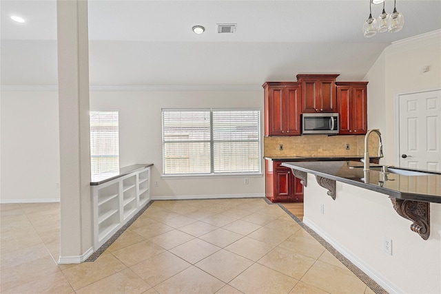 4907 Sundance Hollow Ln, Katy, TX 77494 - kitchen with stainless steel microwave, reddish brown cabinets, crown molding, a breakfast bar area, and light tile patterned flooring
