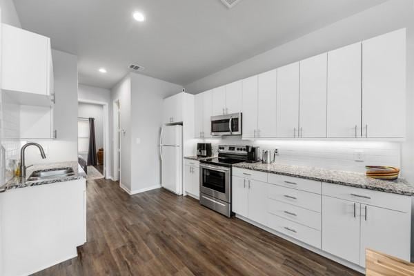 4908 Paradigm Ln, Spring, TX 77379 - kitchen with appliances with stainless steel finishes, a sink, recessed lighting, light stone counters, and dark wood-style floors