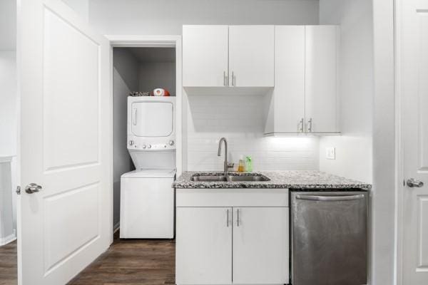 4908 Paradigm Ln, Spring, TX 77379 - kitchen featuring dishwasher, stacked washer and clothes dryer, a sink, and dark wood-style floors