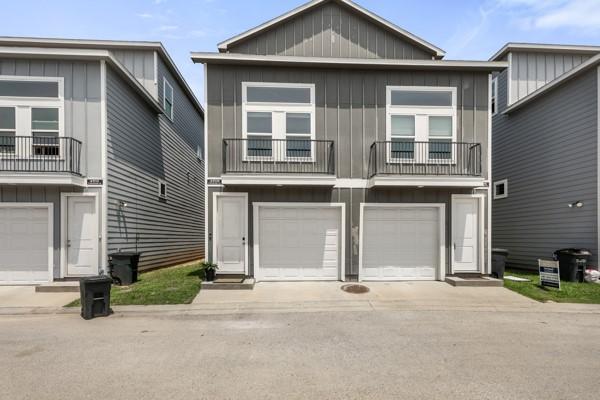 4908 Paradigm Ln, Spring, TX 77379 - view of front facade with a balcony, board and batten siding, concrete driveway, and an attached garage