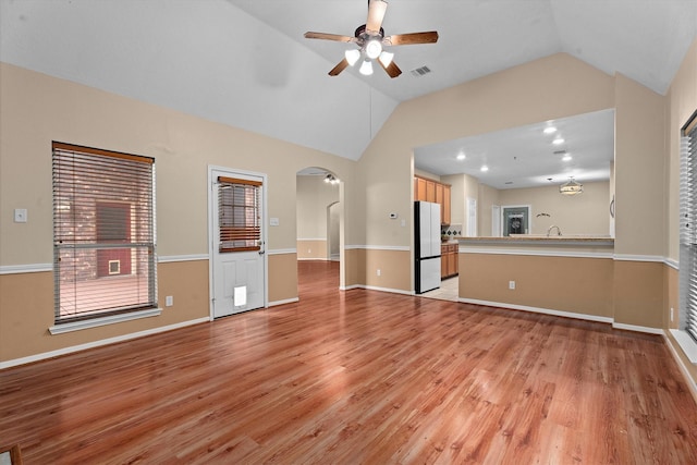 19918 Cypresswood Lake Dr, Spring, TX 77373 - unfurnished living room with lofted ceiling, light wood-style flooring, arched walkways, a ceiling fan, and baseboards