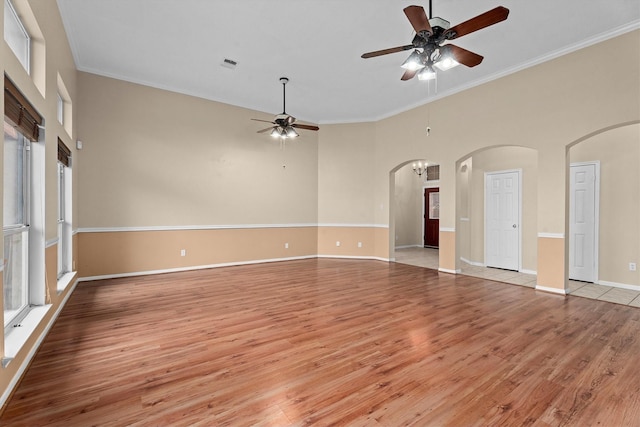 19918 Cypresswood Lake Dr, Spring, TX 77373 - empty room with a ceiling fan, light wood-style flooring, arched walkways, crown molding, and baseboards