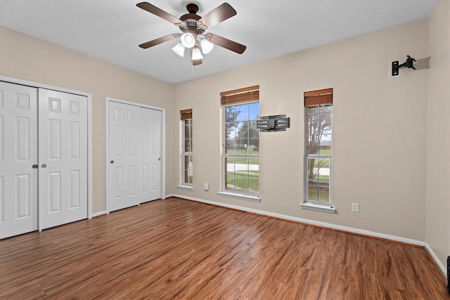19918 Cypresswood Lake Dr, Spring, TX 77373 - unfurnished bedroom featuring two closets, wood finished floors, baseboards, and ceiling fan