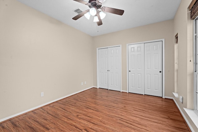 19918 Cypresswood Lake Dr, Spring, TX 77373 - unfurnished bedroom with two closets, wood finished floors, baseboards, and ceiling fan