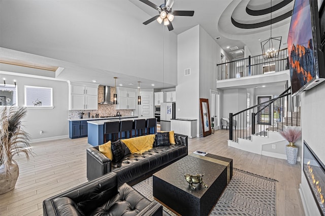 3002 Secret Lagoon Ln, Texas City, TX 77568 - living area with a tray ceiling, baseboards, light wood-style floors, a chandelier, and a towering ceiling