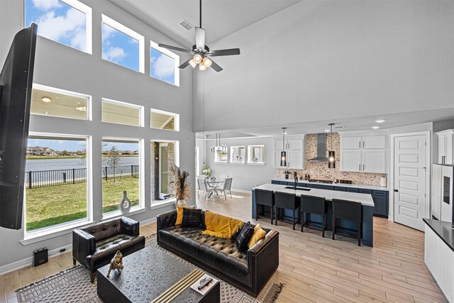3002 Secret Lagoon Ln, Texas City, TX 77568 - living room with high vaulted ceiling, a ceiling fan, light wood-style floors, a water view, and baseboards
