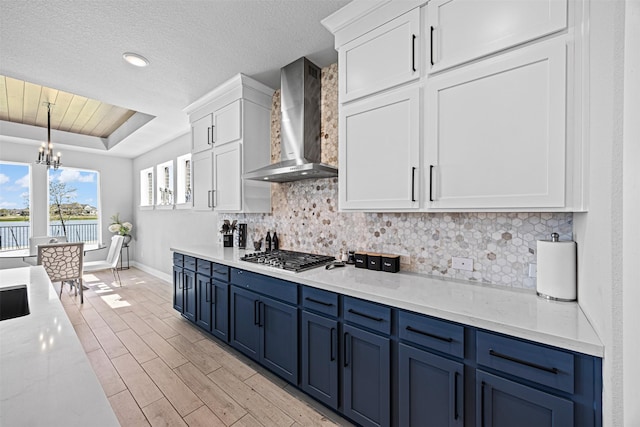 3002 Secret Lagoon Ln, Texas City, TX 77568 - kitchen featuring wall chimney range hood, stainless steel gas stovetop, blue cabinets, baseboards, and tasteful backsplash