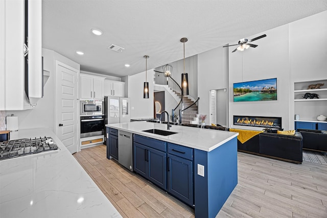 3002 Secret Lagoon Ln, Texas City, TX 77568 - kitchen featuring a sink, blue cabinets, stainless steel appliances, open floor plan, and light wood-style floors