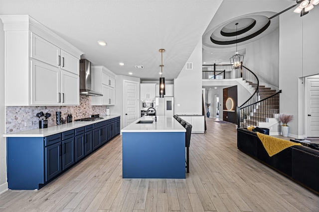 3002 Secret Lagoon Ln, Texas City, TX 77568 - kitchen with blue cabinets, wall chimney range hood, a sink, appliances with stainless steel finishes, and decorative backsplash