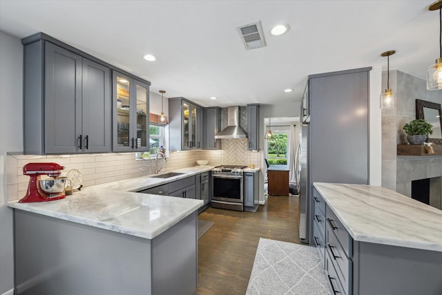 5211 Briarbend Dr, Houston, TX 77035 - kitchen featuring wall chimney exhaust hood, a sink, stainless steel range with gas cooktop, gray cabinetry, and a peninsula