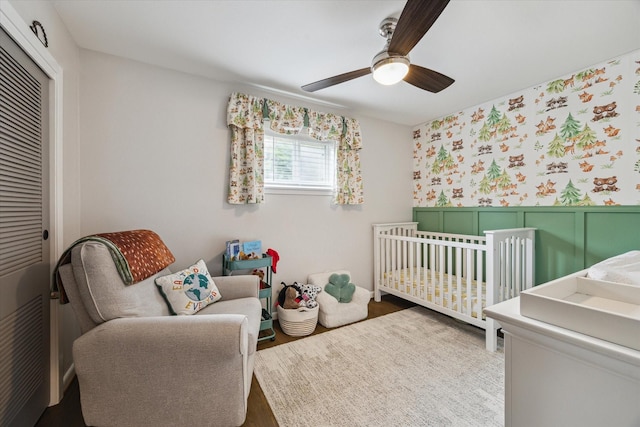 5211 Briarbend Dr, Houston, TX 77035 - bedroom with a closet, a crib, wainscoting, ceiling fan, and wallpapered walls