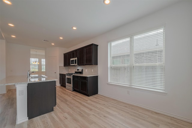 23922 Olivenza Trl, New Caney, TX 77357 - kitchen with appliances with stainless steel finishes, light wood-type flooring, backsplash, light stone counters, and recessed lighting