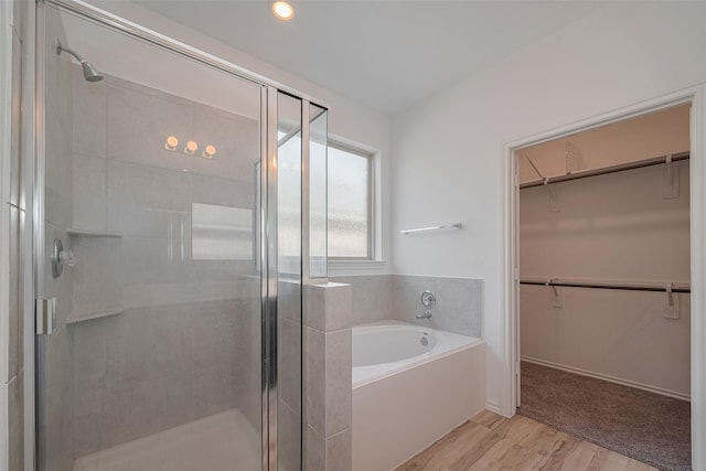 23922 Olivenza Trl, New Caney, TX 77357 - full bathroom featuring a bath, a stall shower, a spacious closet, and wood finished floors