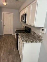 13323 S Thorntree Dr, Houston, TX 77015 - kitchen featuring stainless steel microwave, gas stove, dark wood-style flooring, and white cabinets