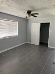 13323 S Thorntree Dr, Houston, TX 77015 - unfurnished bedroom featuring baseboards, a ceiling fan, and a textured ceiling