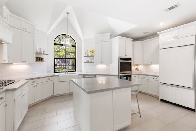 31 Wood Cove Dr, The Woodlands, TX 77381 - kitchen with appliances with stainless steel finishes, open shelves, a sink, a kitchen island, and high vaulted ceiling