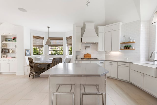 31 Wood Cove Dr, The Woodlands, TX 77381 - kitchen featuring a sink, custom range hood, open shelves, decorative backsplash, and light countertops