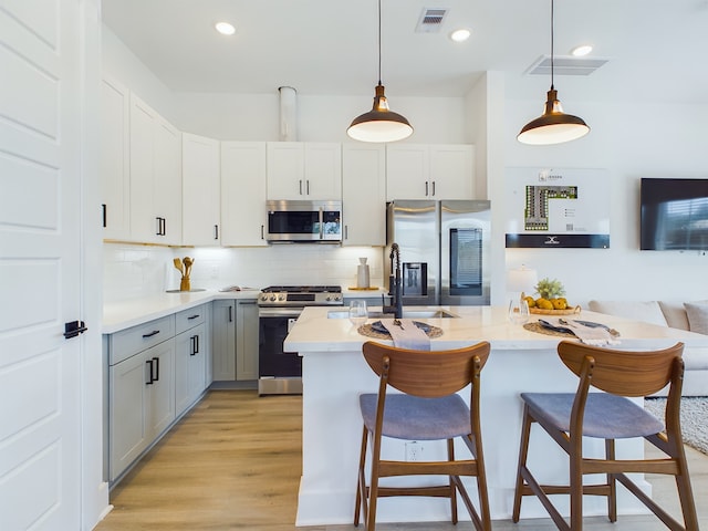 3004 Jensen Springs Ln, Houston, TX 77026 - kitchen featuring stainless steel appliances, light countertops, gray cabinets, a breakfast bar area, and recessed lighting